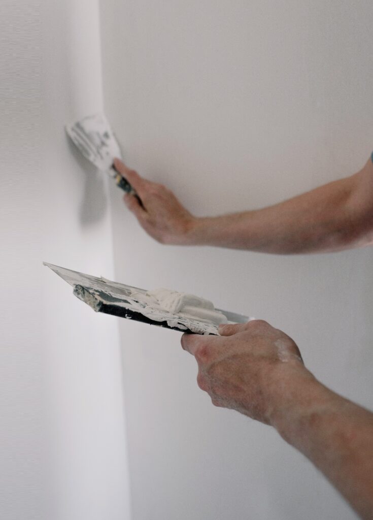 view of workers arms as he applyings plastering agent to wall