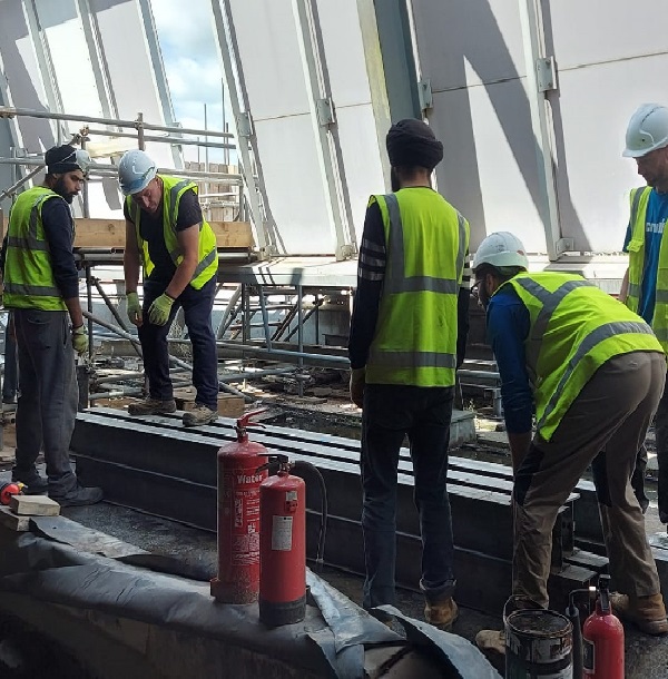 members of the team in high vis jackets lifting trusses or beams inside a building