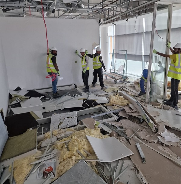 Construction workers in high vis jackets and helmets working on an interior soft strip demolition.